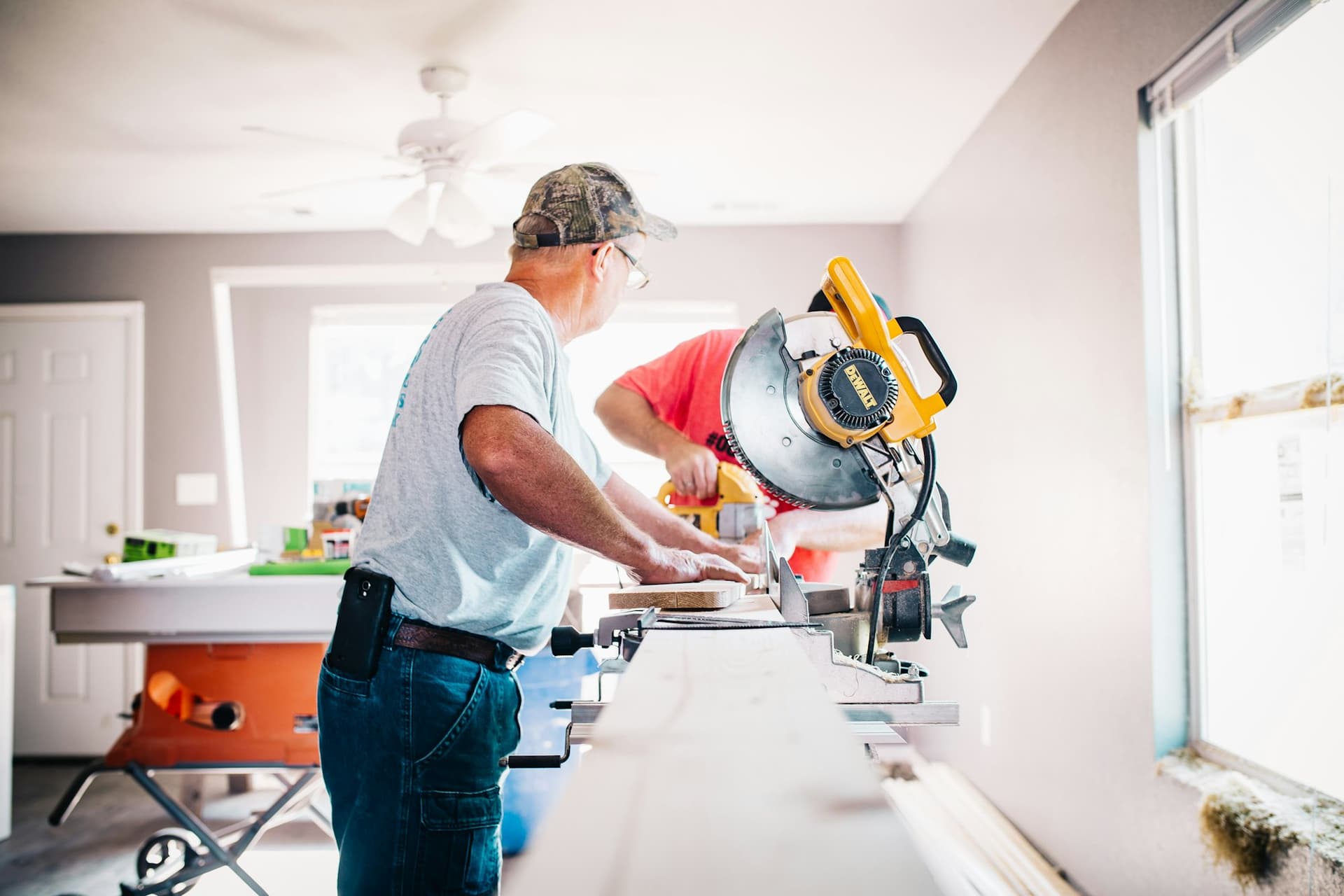 Tradesman cutting timber with a mitre saw inside a home under renovation