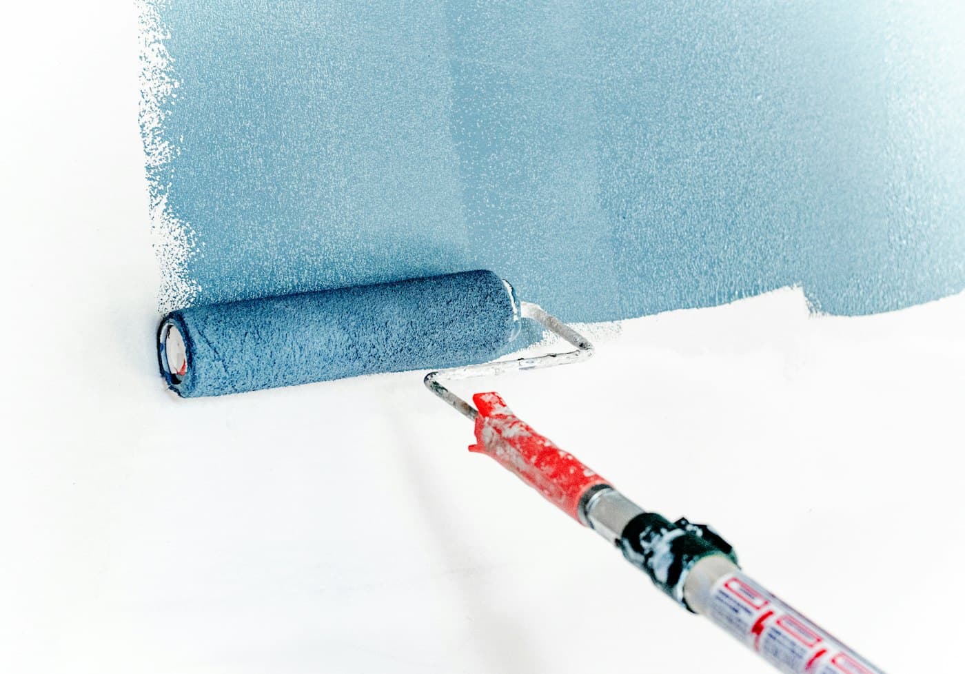 Paint roller applying a fresh coat of blue paint